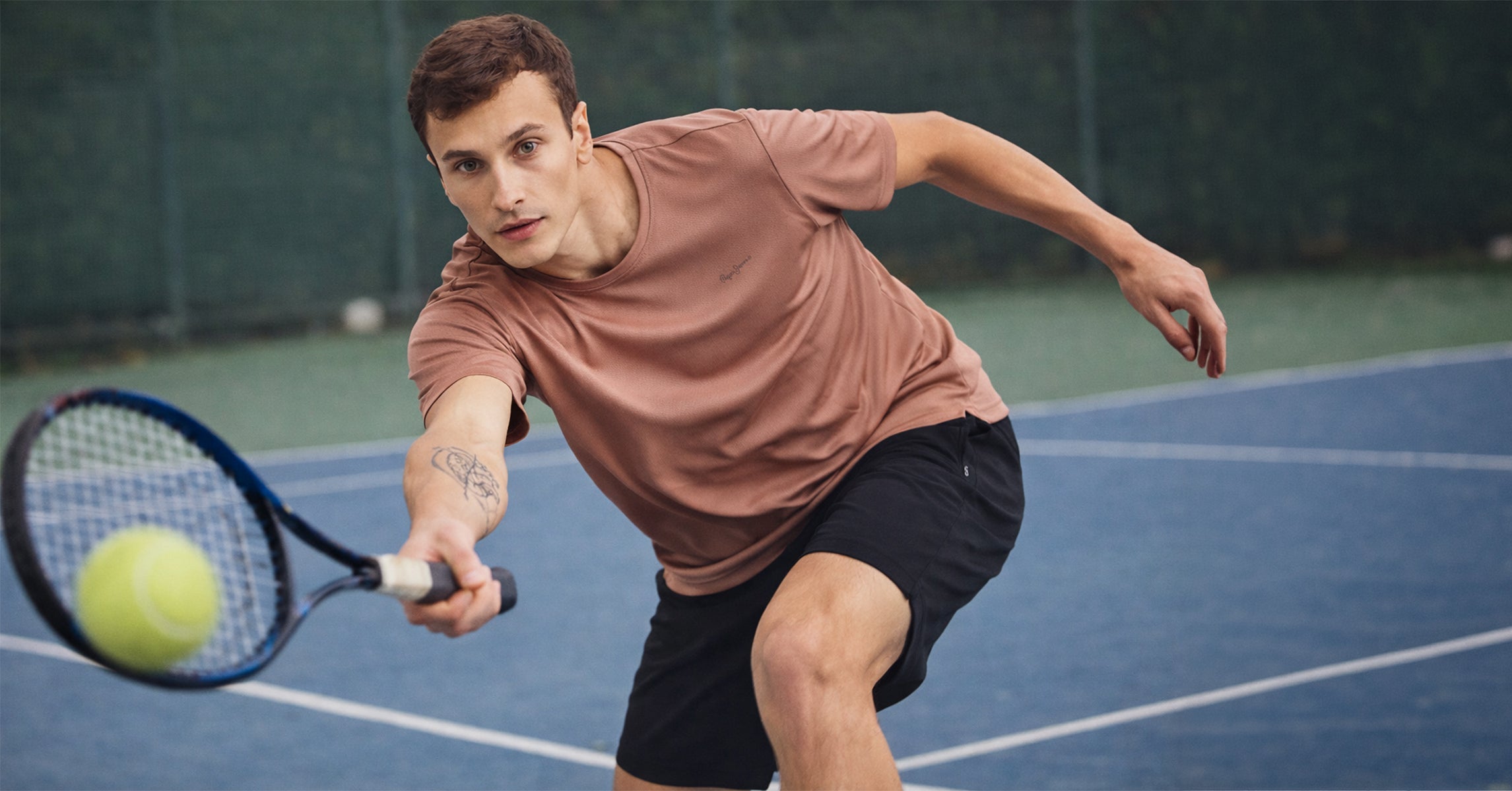 Man playing tennis on a blue court with a racket and ball.